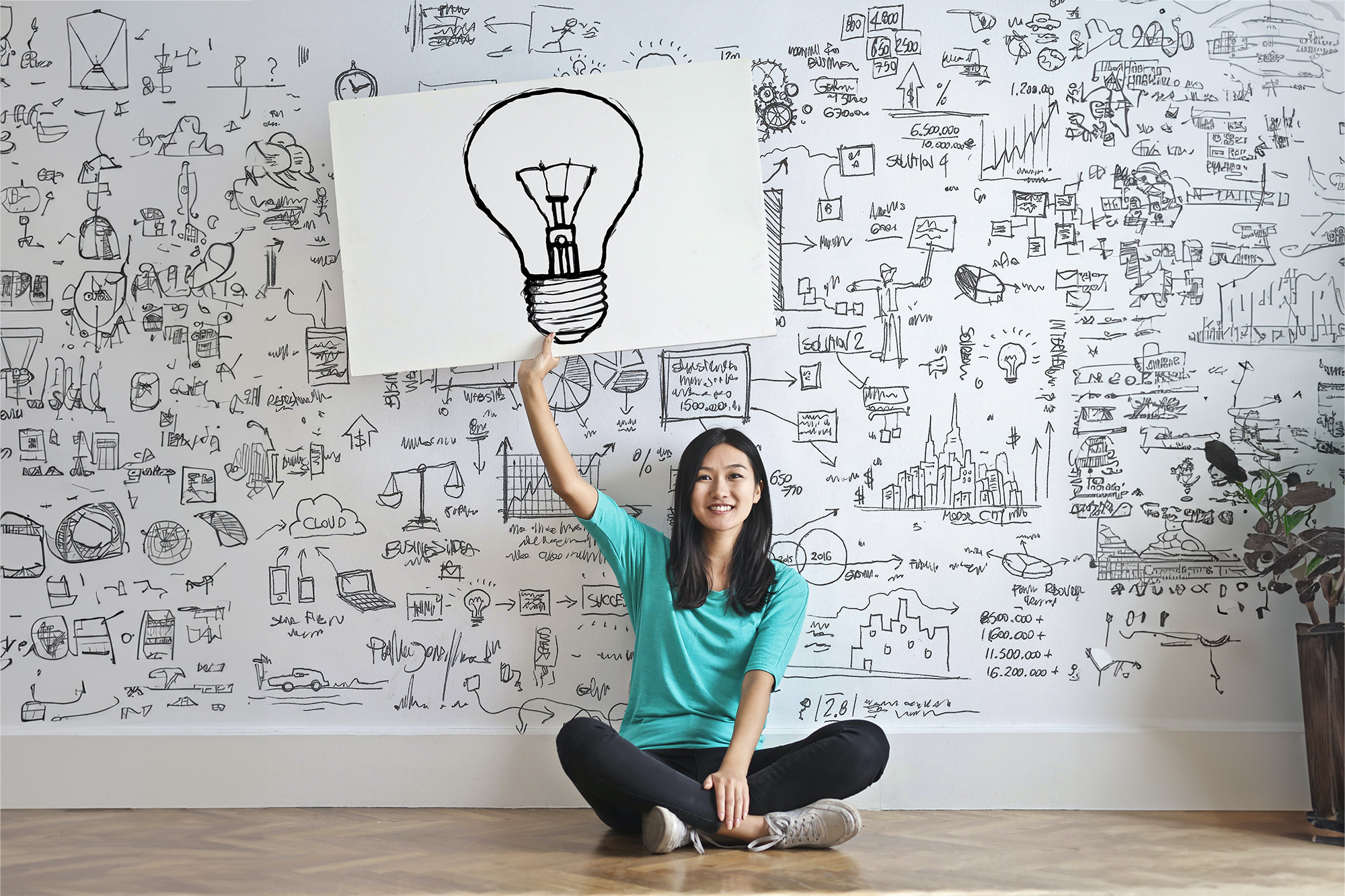 Photo of a person holding a drawing of a lightbulb above their head